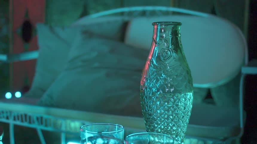 Bottle and glasses on a table outdoors at night
