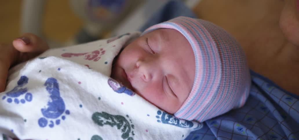 A mother in a hospital bed holds her newborn child