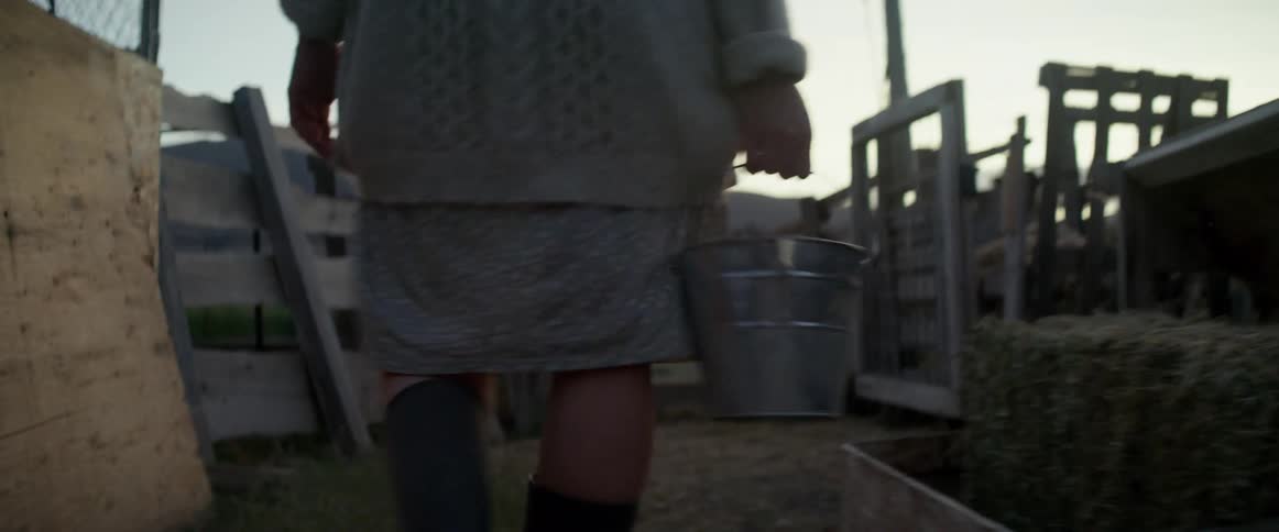 A woman carries a bucket to the animals