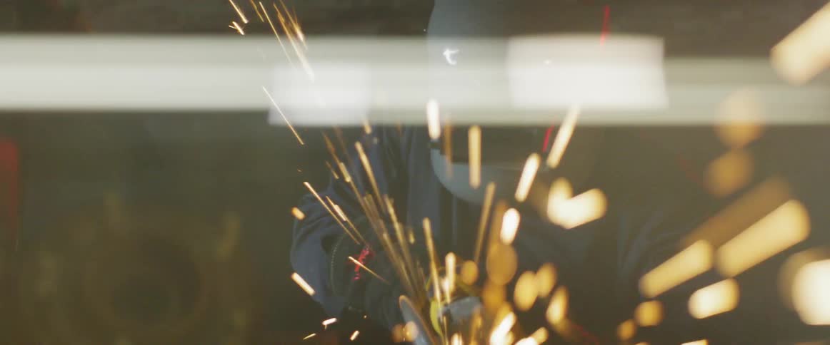A welder works in a shop with sparks flying all around