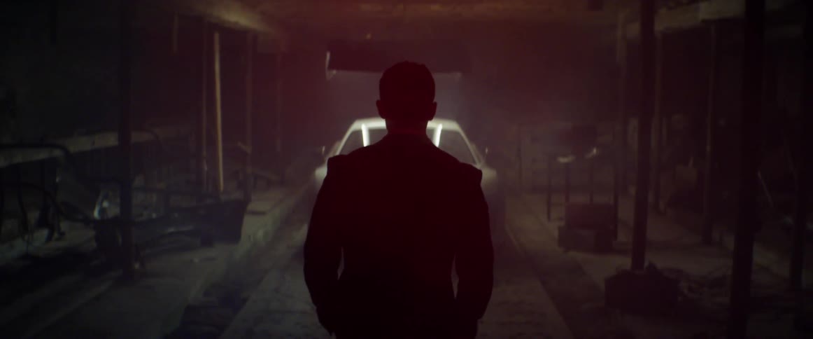 A man walking towards a vehicle in a dim garage
