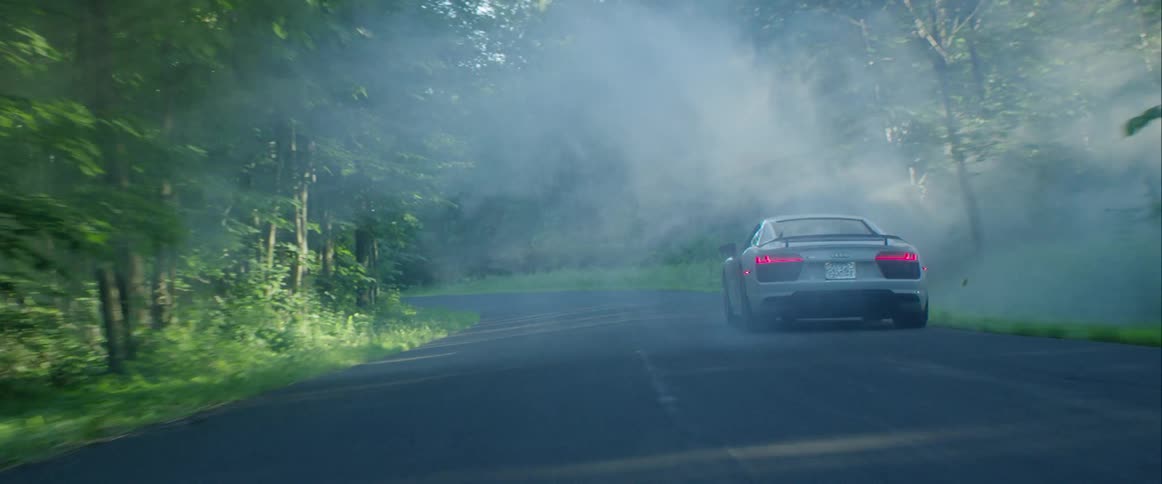 A sports car drives on a road in the woods