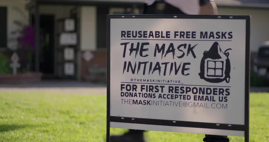 A white man puts a face mask sign in a front yard