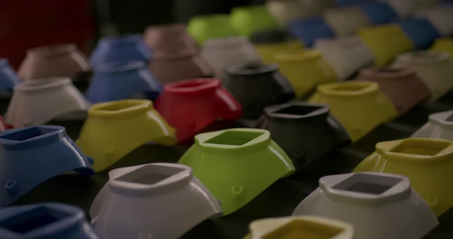 Rows of various colored containers flow past on conveyor belt