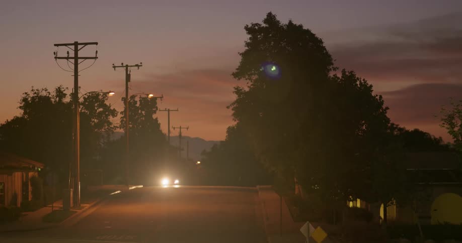 Vehicles drive through a neighborhood at night