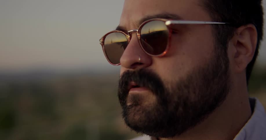 A man wearing sunglasses is standing outdoors