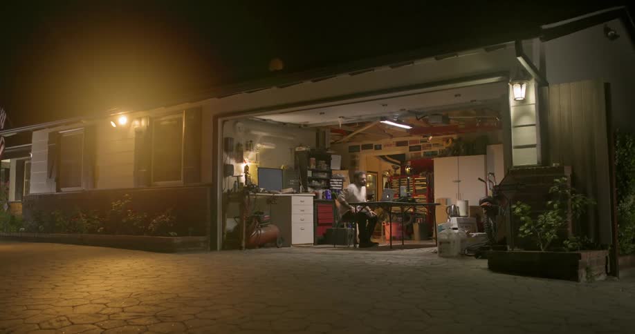 A man walks and sits at the table in his garage
