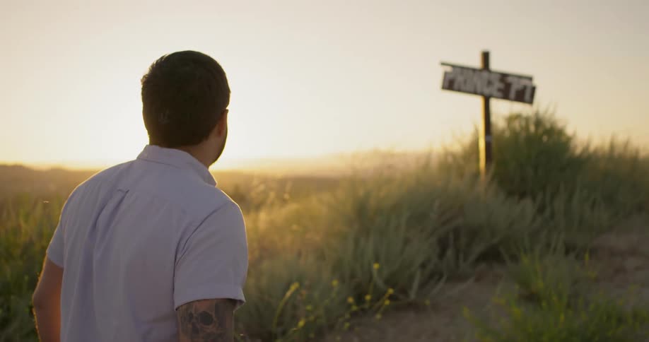 A man comes upon a street sign planted on a hiking trail in a canyon