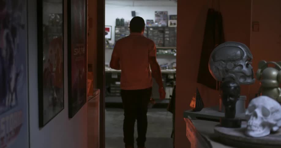 A man walks through an office filled with props and in to another room
