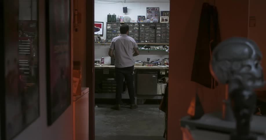 A man in the backroom of building rearranging items on cluttered shelves