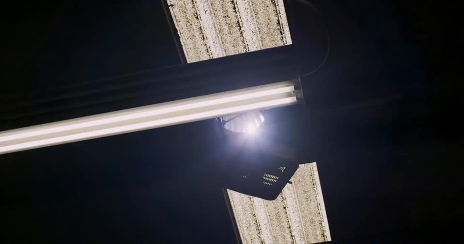 A fan on top of a ceiling and then fluorescent lights turn on