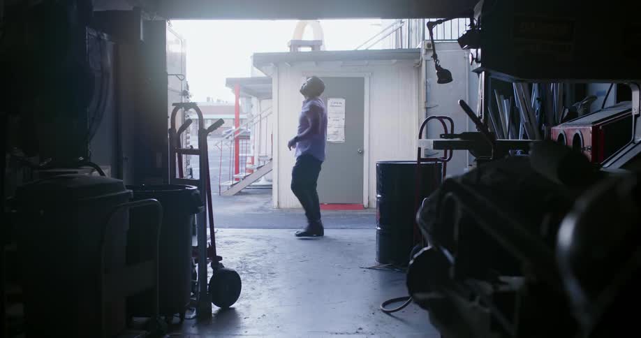 A man lifts up a door to a storage facility and steps inside before closing it