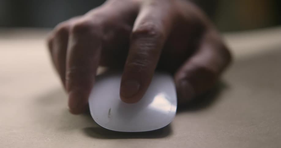 Close up of a mans hand using a mouse by moving across a surface