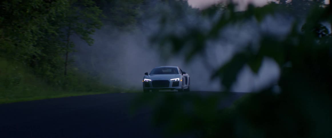 A sports car drives through fog in the woods