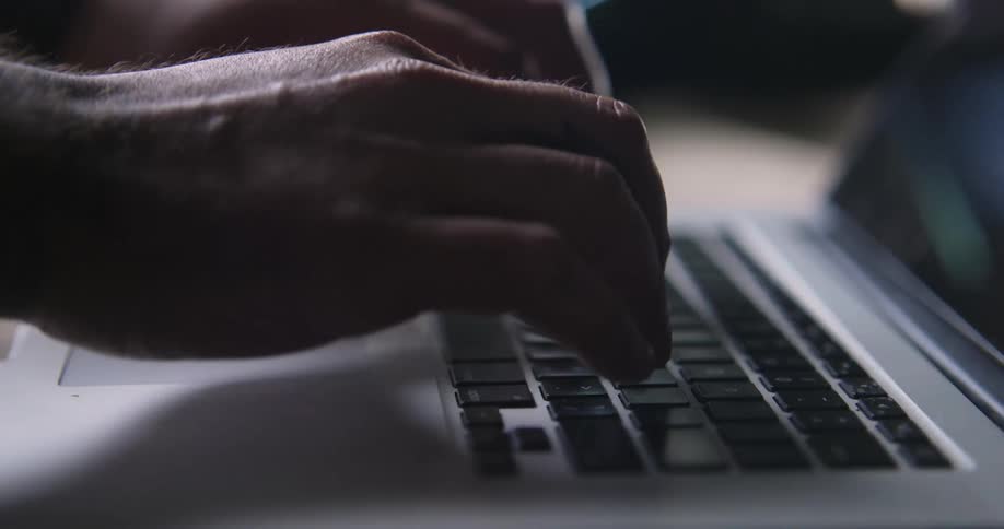 A white person types on a laptop keyboard