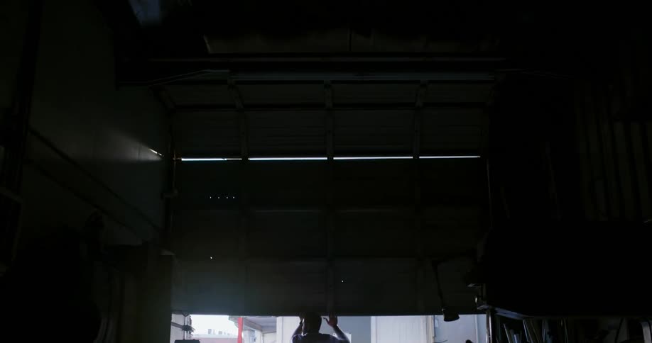 A man manually opening the door to a garage