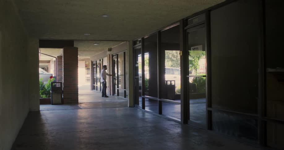 A man walks down the hall and enters the building
