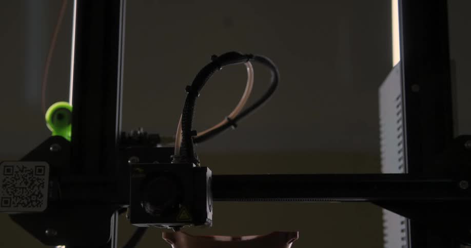 A 3d printer scans a brown object moving back and forth underneath a square box