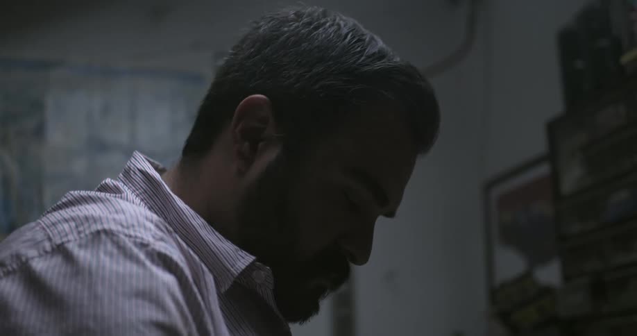 A man working in a shop looks around at parts