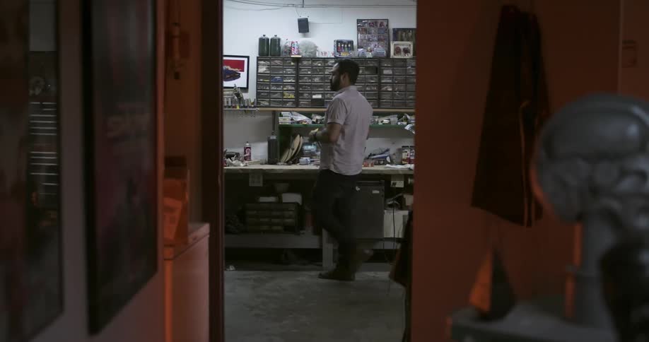 A man working in a shop walks in to a room filled with parts