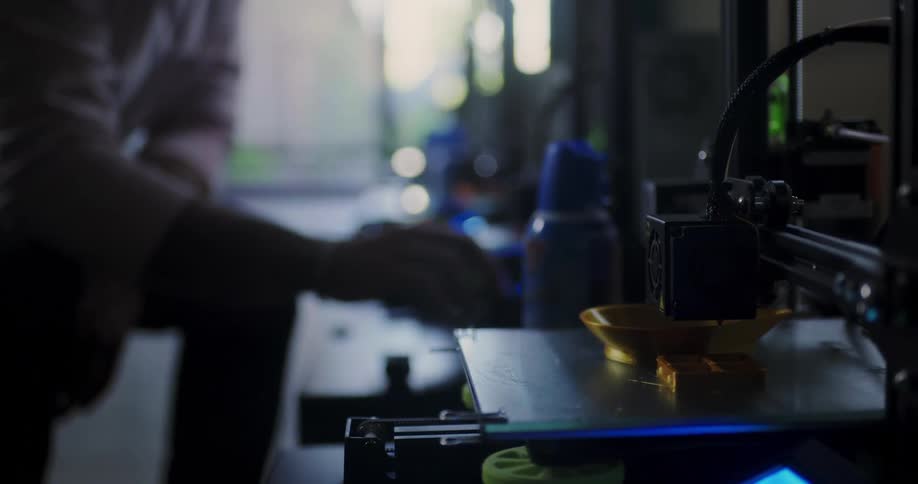 Person uses 3d printer to print an object using gold material