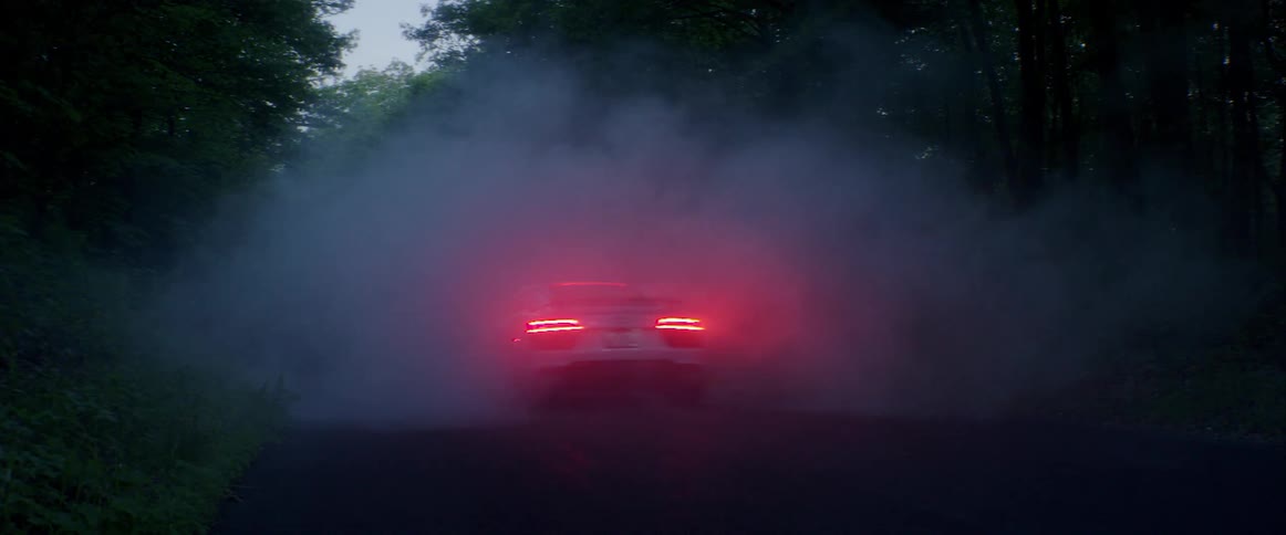 A car drives down a misty road