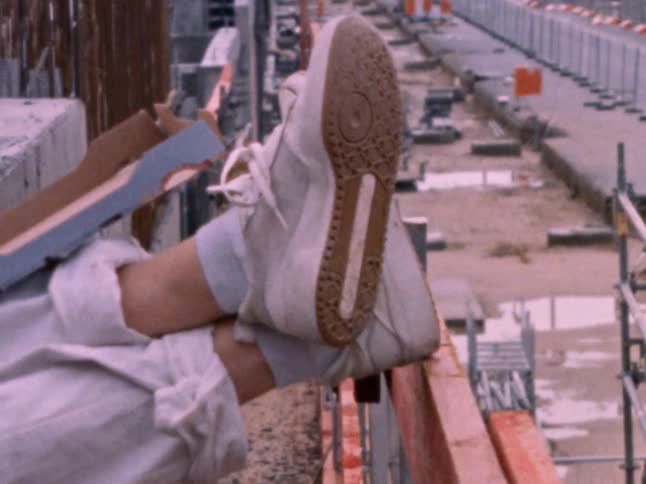 A person props their feet up on a railing at an industrial site