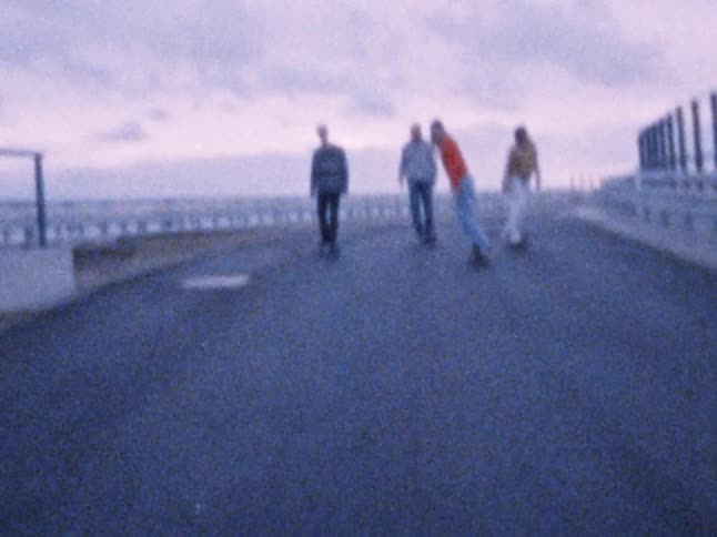 Four young men are having fun skateboarding together on a cloudy day