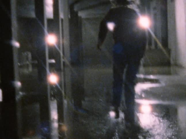 A white male skateboards through a building with water puddles on the floor