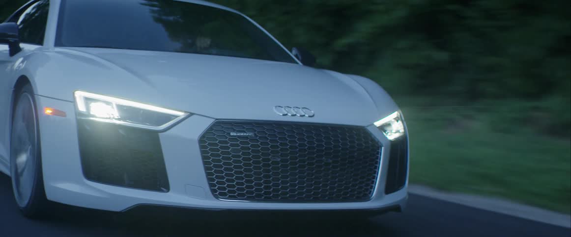 A car is driving down a road with its headlights on