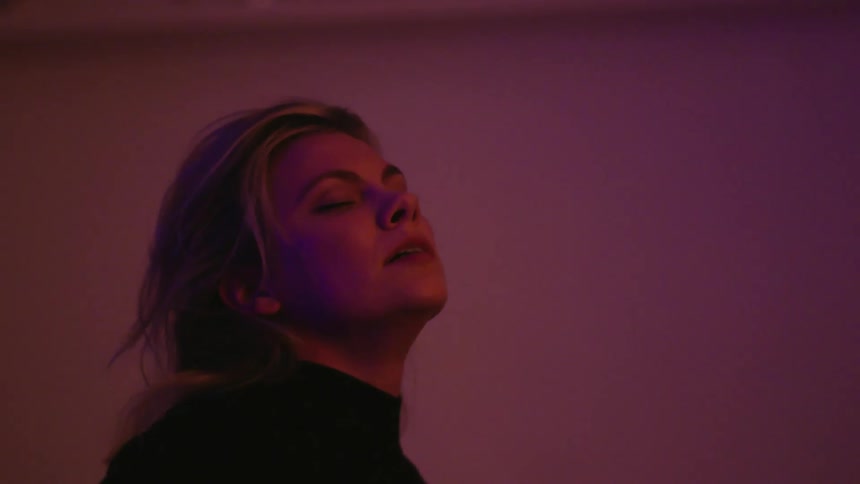 Woman straightens from backward dip as lights cast area various colors