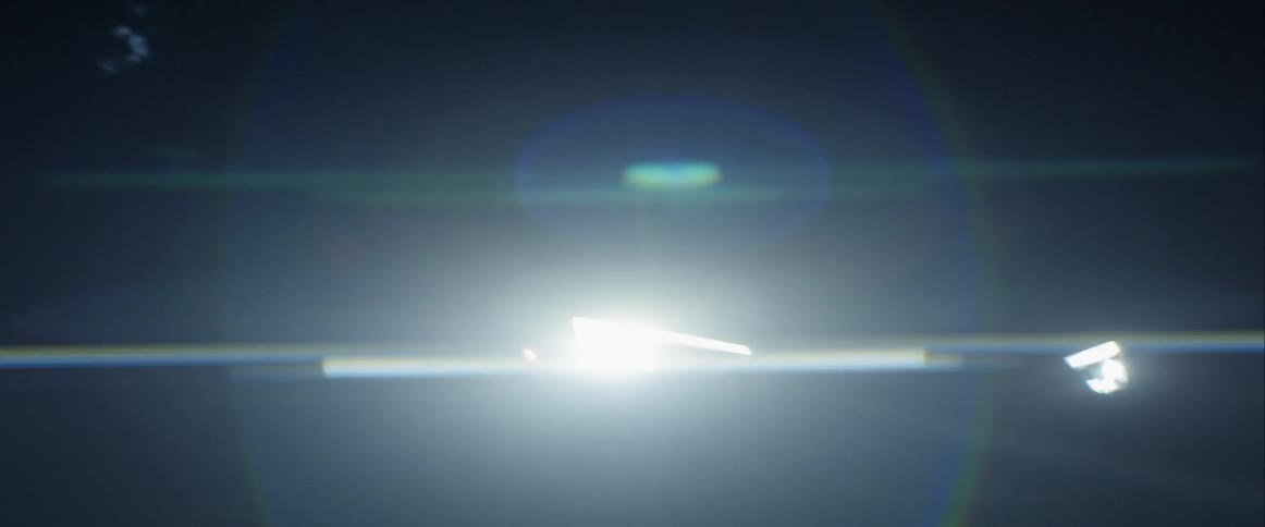A car's lights shining as it speeds along a road