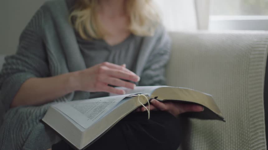 A woman is reading a book while sitting on a couch
