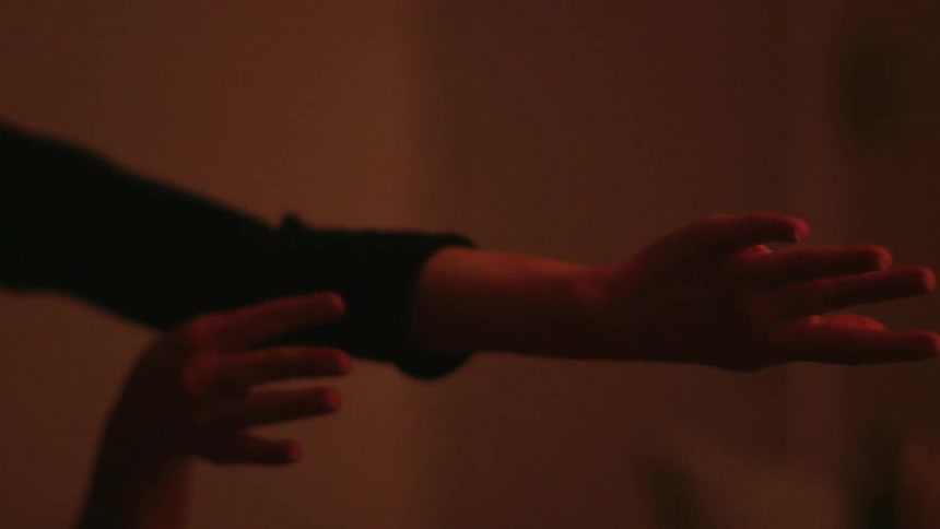 Hands of a woman doing interpretative dance in a room with colorful lights