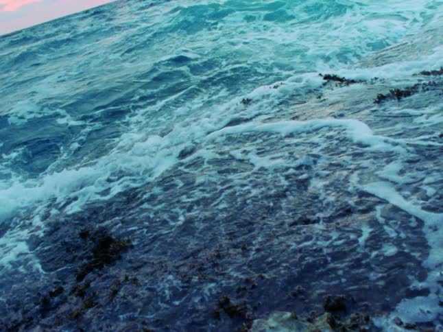 A rocky beach with waves with the sky in the background