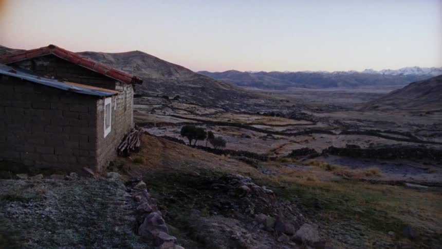 A small building in a rural area sits near a large mountain valley