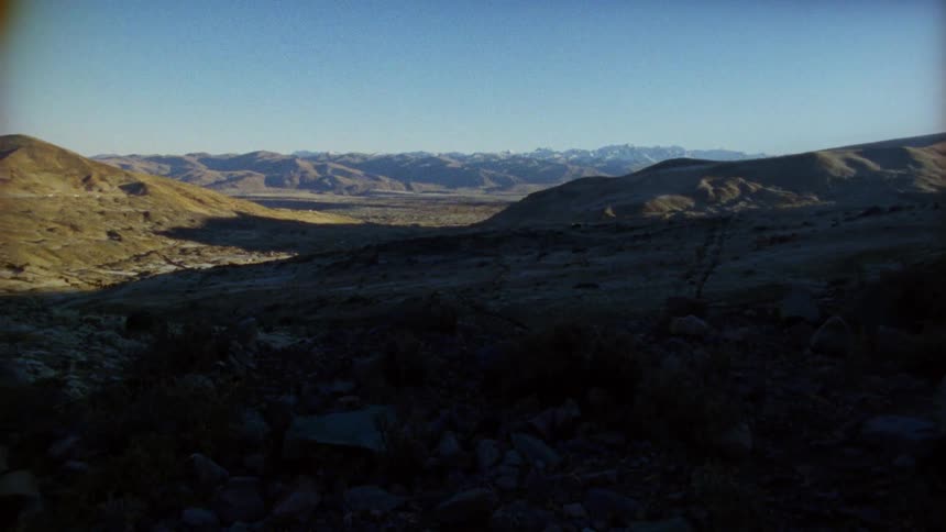 A vast rocky mountain valley in the shadow of a mountain