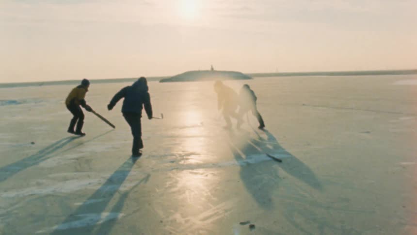 Four people play hockey on a frozen lake