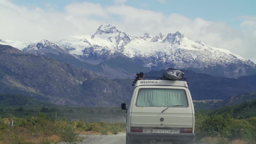 Van travels on a road heading towards the snow covered mountains