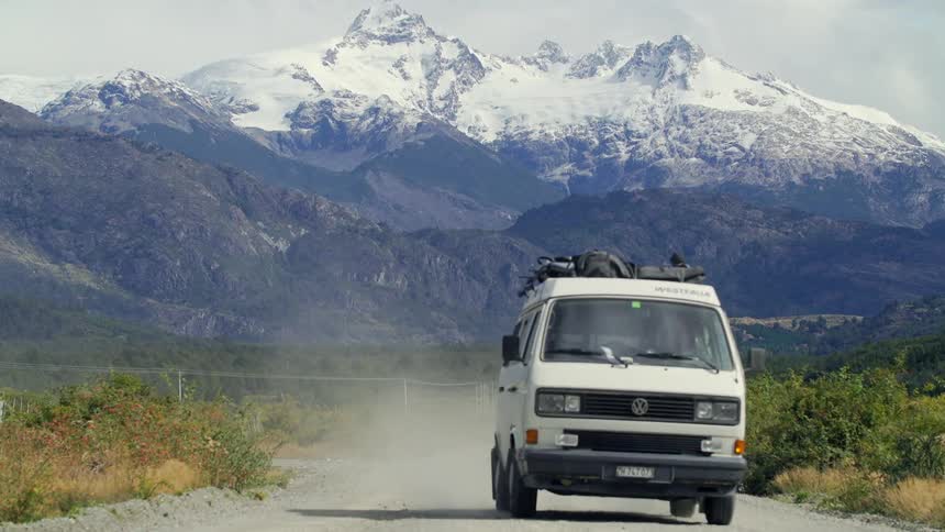 A van drives down a dirt road through a mountain valley