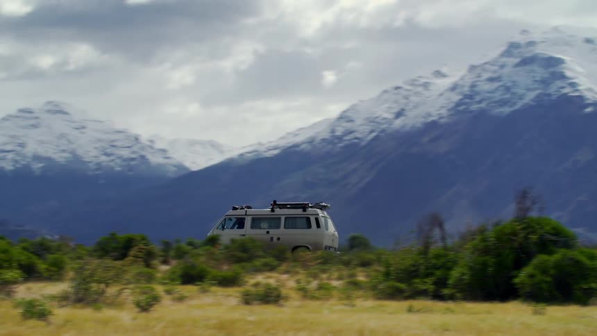 A van drives past the tall mountains