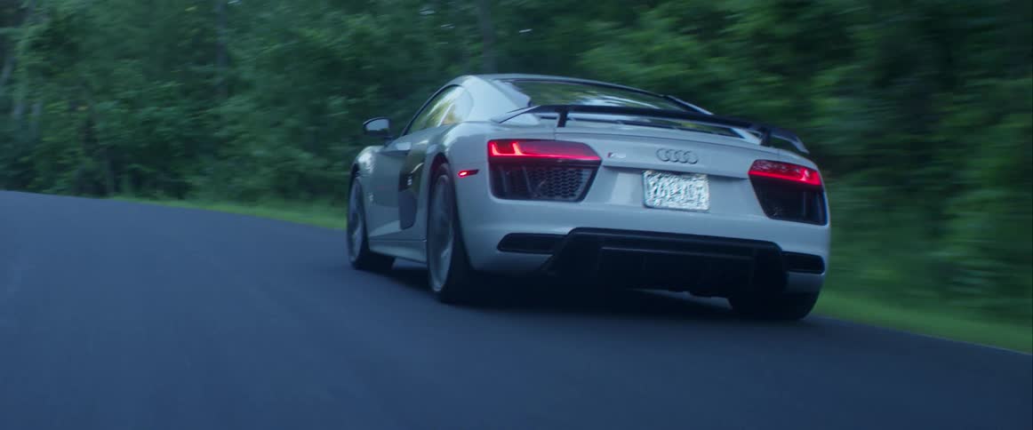 A sports car drives on a road in the woods