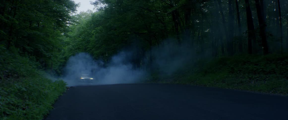 A car drives through a smoky country road