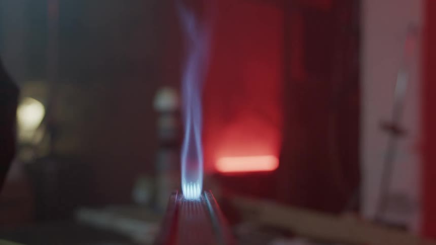 Person in long sleeves lights tall blue flame using lighter