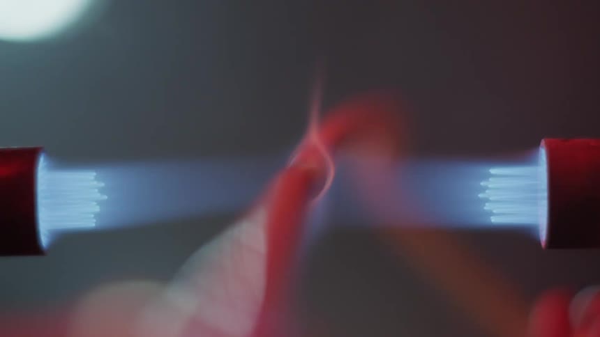 A piece of metal being held in a blue flame