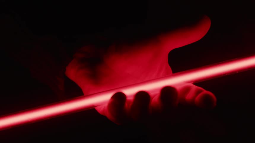 A person holds a glowing red tube in their hand