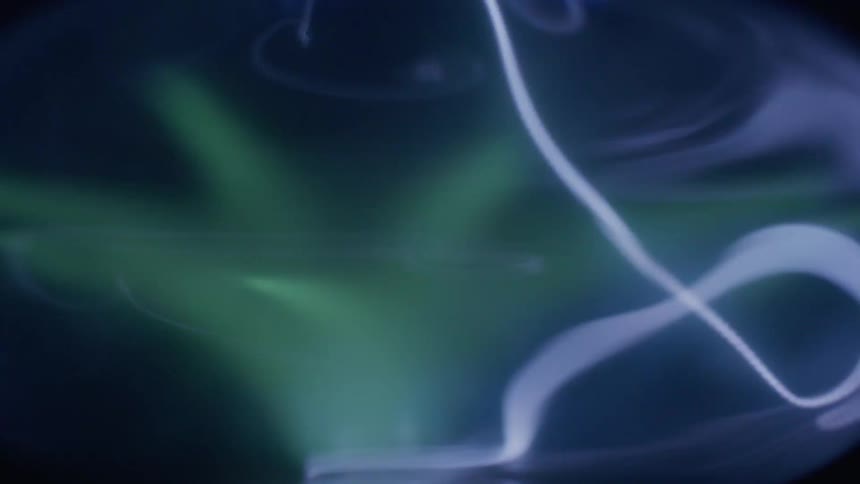 A light show with green strobes and bluish white strings of light moving