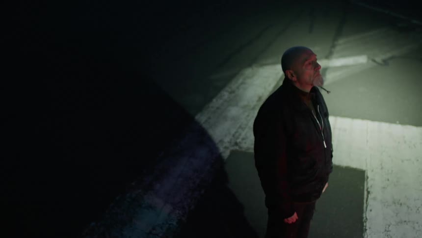 A man stands outside at night with a light flashing around on him