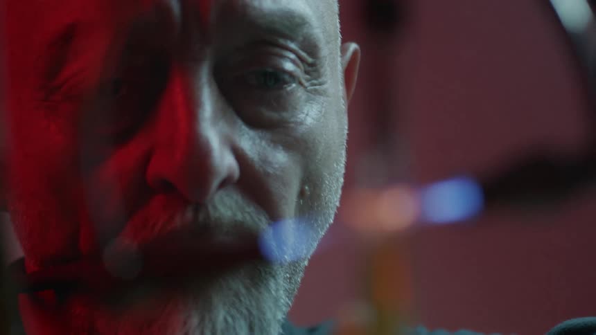 Bearded man watches a laser device cut into a glass tube
