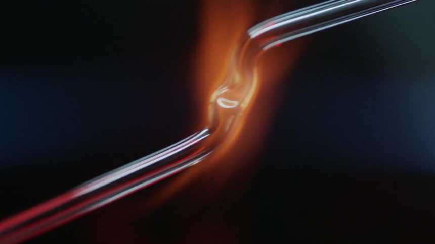 A thin metal glass pipe is shape over an open flame
